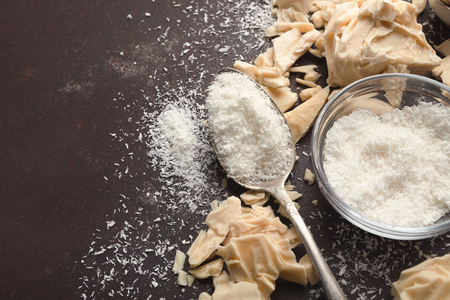 White chocolate pieces crushed on dark background and coconut flakes closeup, copy space. Sweet wallpaper, confectionery shop advertising and cooking ingredients conceptの写真素材