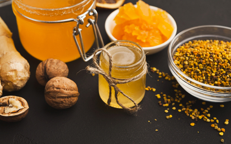 Honey assortment, closeup. Composition with full glass jars, pollen bowl, nuts and ginger. Sweet background, wallpaperの写真素材