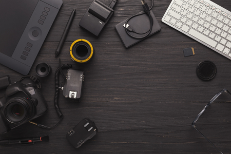 Top view on workplace of photographer or creative designer. Desk with graphic tablet, laptop, camera, lens and other photographic equipment, copy spaceの写真素材