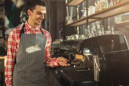 Barman making espresso in modern coffee machine. Man preparing bracing beverage. Small business and professional coffee brewing conceptの写真素材
