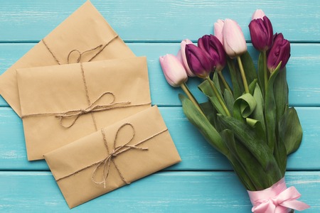 Bunch of colorful tulips and small craft presents on blue wood, top view. Spring background, Mothers day or Valentines day greeting card, copy space, flat layの写真素材