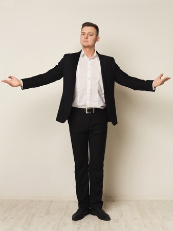 On the top of business world. Excited young businessman keeping arms raised and expressing positivity and success, white studio backgroundの写真素材