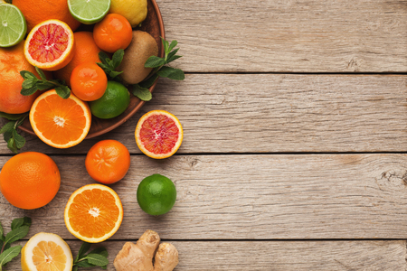 Border of assorted citruses on rustic wooden background, copy space. Top view on oranges, lemons, tangerines and other exotic fruits, flat layの写真素材