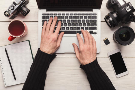 Photographer using blank laptop on workplace with photo equipment, networking or retouching photos, technology and communication concept, top view, copy spaceの写真素材