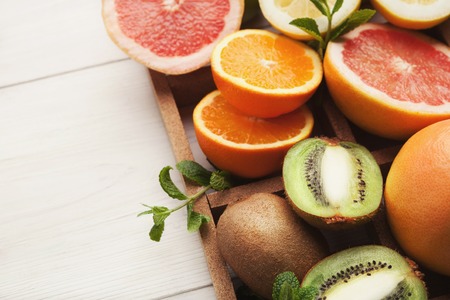 Closeup of assorted citrus fruits in box on white wooden background. Detox, natural vitamins and antioxidants, healthy lifestyle concept, copy spaceの写真素材