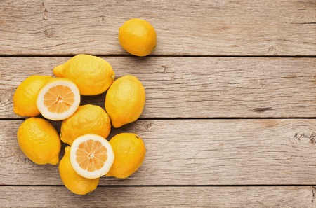 Citruses background. Top view on lemons pile. Mockup for exotic drink recipe, copy space on rustic woodの写真素材