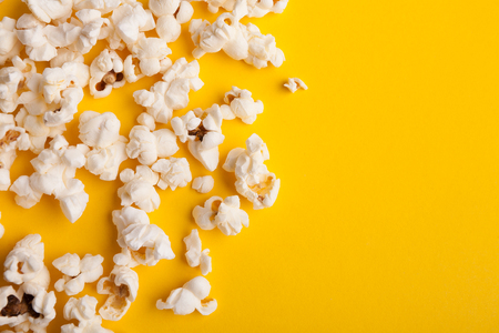 Border of popcorn scattered over yellow background with copy space, top view. Minimalistic design for movie poster, entertainment conceptの写真素材
