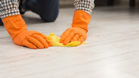 Unrecognizable man washing wooden floor with towel in living-room. Housekeeping, home cleaning and cleaning service concept, copy spaceの写真素材