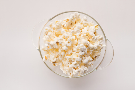 Glass bowl of popcorn isolated on white background, top view. Fast food, cinema snack and entertainment concept, cutoutの写真素材