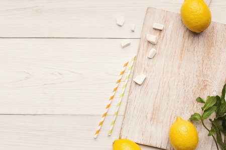 Homemade lemonade background. Lemons, refined sugar, mint and straws - ingredients for refreshing...