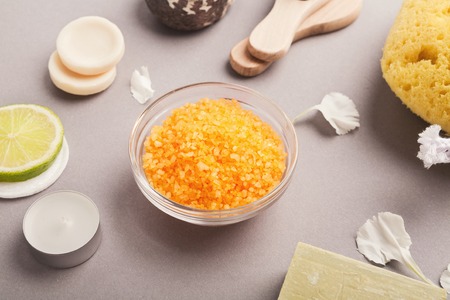 Spa background. Natural sea salt with lemon essential oil and various cosmetology products on gray...