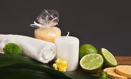 Spa background. Natural skincare and aromatherapy products: candles, sea salt and limes at gray backdrop. Salon or home body care, copy space, side viewの写真素材
