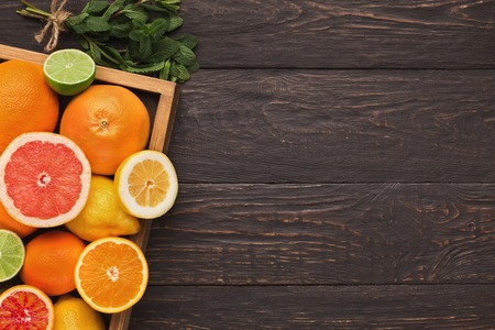 Frame with assortment of citruses on rustic wooden background, copy space. Top view on oranges, lemons, tangerines and other exotic fruits, flat layの写真素材