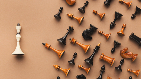 White queen lying separately at other black and wooden chess set on beige background. Individuality and loneliness conceptの写真素材