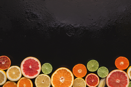 Border of assorted citruses on black background, copy space. Top view on oranges, lemons, tangerines and other exotic fruits, flat layの写真素材