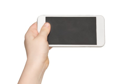 Kid holding blank mobile phone, cutout. Child hand with modern smartphone, white isolated background, copy space on screenの写真素材