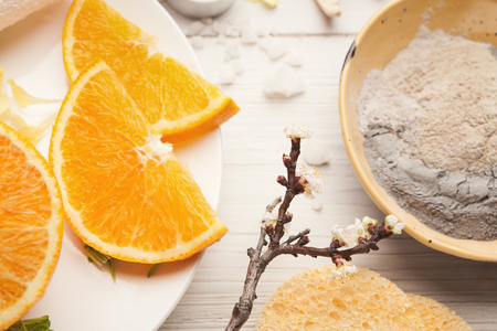 Cosmetology mud mask and orange slices for natural spa treatment on white wooden background. Skincare conceptの写真素材