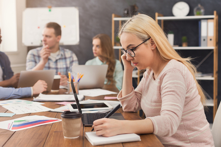 Business team talking about results of their work. Group of cheerful businesspeople discussing new marketing strategy, young woman talking on phone and taking notes, copy spaceの写真素材