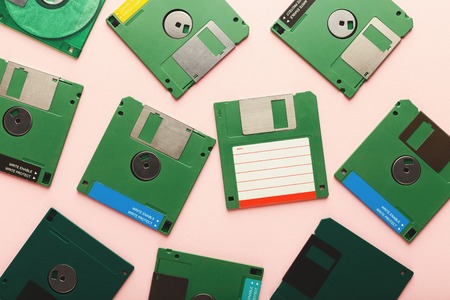 Old floppy disks isolated on pink background. Top view of magnetic retro storage devices, cutout of green diskettes, copy space, flat layの写真素材