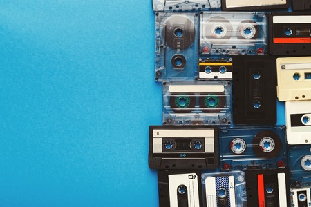 Creative border of vintage cassettes. Old retro tapes on blue background, top view with copy space, multimedia conceptの写真素材