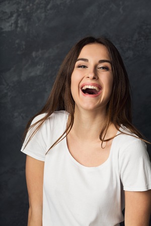 Young laughing attractive woman portrait. Beautiful girl having fun, dark background
