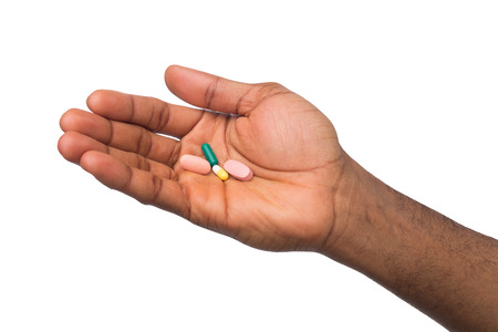 African-american hands holding a pill in one hand and plate of tablets in other isolated on white background. Health care, treatment conceptの写真素材