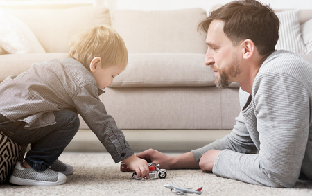 Loving father and little boy playing together with toys in living room.の写真素材