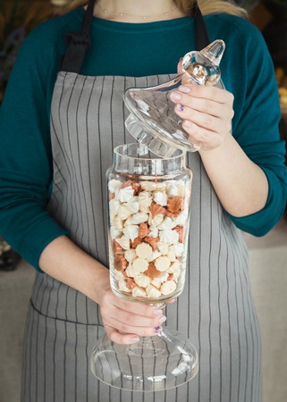 Chef holding glass jar with delicious colourful meringues for candy barの写真素材