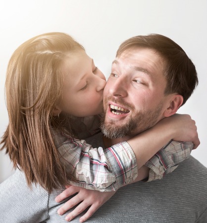 Portrait of daughter hugging and kissing her father in cheek at home