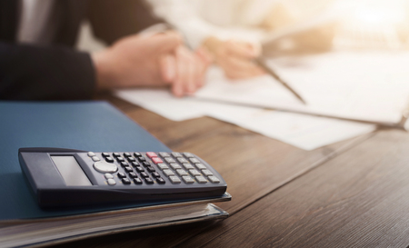Calculator on foreground, business people discussing financial problems, accounting and banking background, copy spaceの写真素材