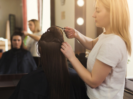 Woman getting hairdo at salon. Professional hair stylish pinning up the hairの写真素材