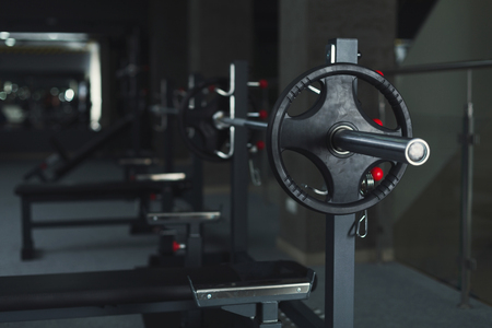 Modern gym interior with weightlifting equipment. Closeup of dumbbell on special rack. Healthy lifestyle, bodybuilding concept, copy spaceの写真素材