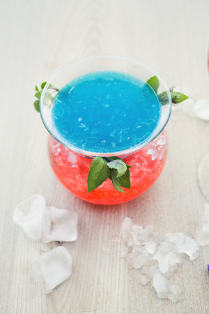 Traditional cocktail in modern serving. Soft drink with blue curacao syrup, coconut rum and pineapple juice. Cold beverage on wooden table with copy space. Mockup for blue hawaii recipeの写真素材