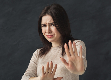 Woman showing no with her hand. Stop sign of discrimination or anti violence symbol, black studio...