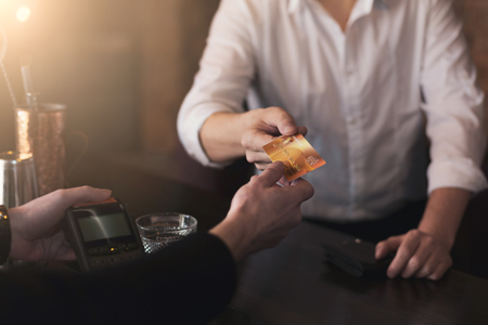 Man giving credit card to bartender in pub, cashless payment for drink, copy spaceの写真素材
