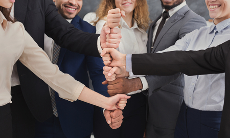 Positive business team putting fists on top of each other, copy space. Agreement, harmony,...