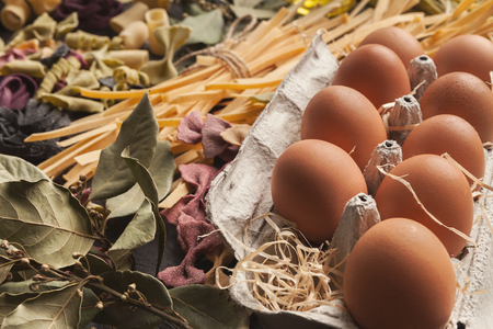 Mixed raw colorful italian pasta with eggs, various vegetables and spices on rustic wooden...