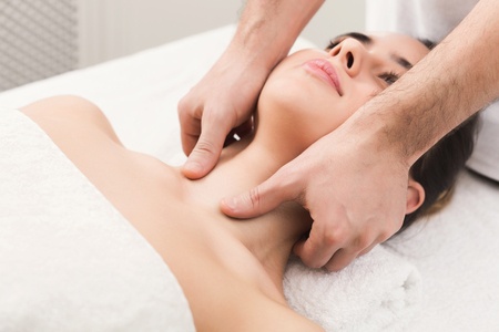 Woman enjoying anti aging facial massage. Pretty girl getting professional skin care at wellness center. Relaxation, beauty, spa and face treatment concept, copy space, closeupの写真素材