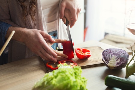 Closeup of unrecognizable couple cooking healthy food together in their loft kitchen at home. Cutting vegetables, preparing vegetarian salad, copy spaceの写真素材