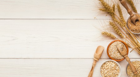 Natural organic grains with ears of wheat on white wooden table, top view, copy spaceの写真素材