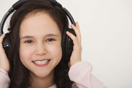 Technology and entertainment. Cute little girl enjoying music using headphones, closeup, copy spaceの写真素材