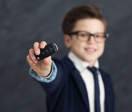New car keys in cute little businessman hands, studio background.
