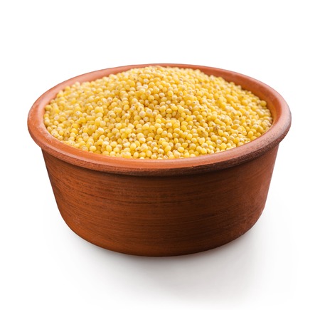 Dry organic millet in clay rustic bowl, isolated on white background