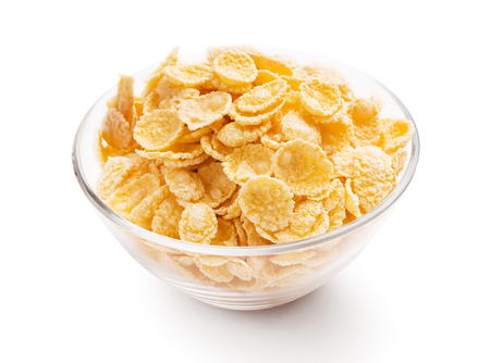 Yellow corn flakes in glass bowl over white background