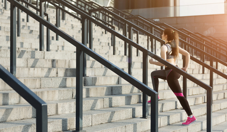 Slim woman jogging upstairs at sports stadiumの写真素材