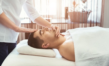 Handsome man getting professional facial massage in spa salonの写真素材