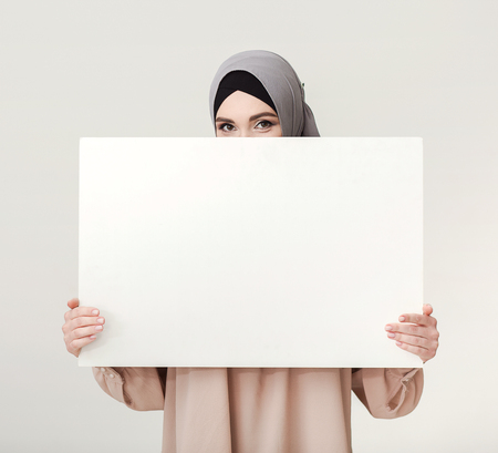 Islamic woman hiding behind white blank board, copy spaceの写真素材
