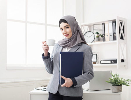 Portrait of arabic business woman at office. Ceo with folder and cup of coffeeの写真素材