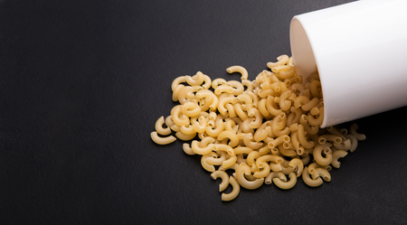 Italian pasta from durum gluten free flour scattering on black background, copy spaceの写真素材