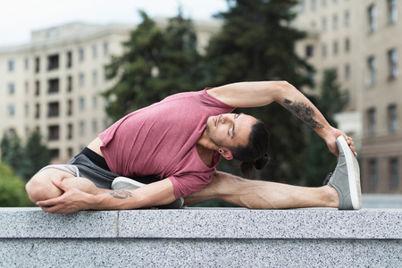 Man doing yoga stretching exercise outdoors in city centerの写真素材